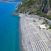 Spiaggia con file di ombrelloni vicino al mare turchese.