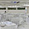 Sala da pranzo moderna con tavoli bianchi e sedie trasparenti.
