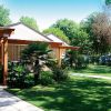 Un bungalow con terrazza coperta, circondato da prati e alberi.