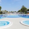 Una piscina con lettini e ombrelloni, due vasche idromassaggio in primo piano.