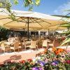 Un bar esterno con tavoli e sedie sotto grandi ombrelloni, circondato da fiori colorati.