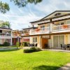 Complesso residenziale con appartamenti a due piani, balconi fioriti e giardino verde ben curato.